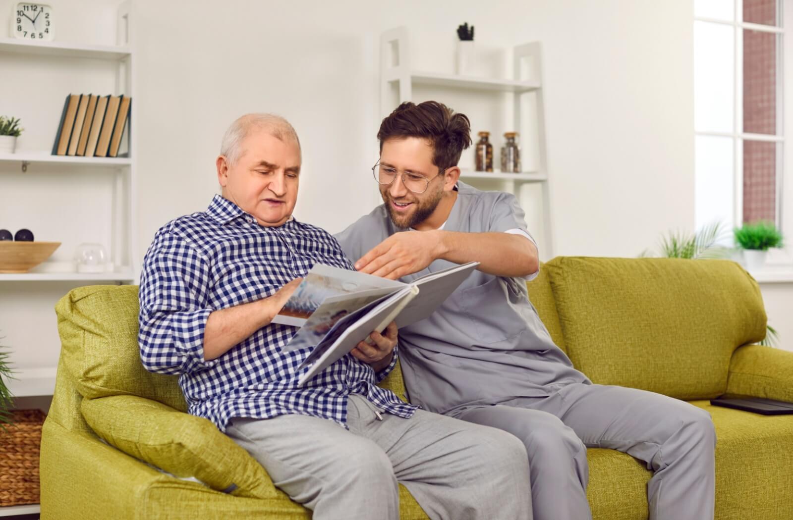 A senior and caregiver look through a family album together to reminisce on fond memories.
