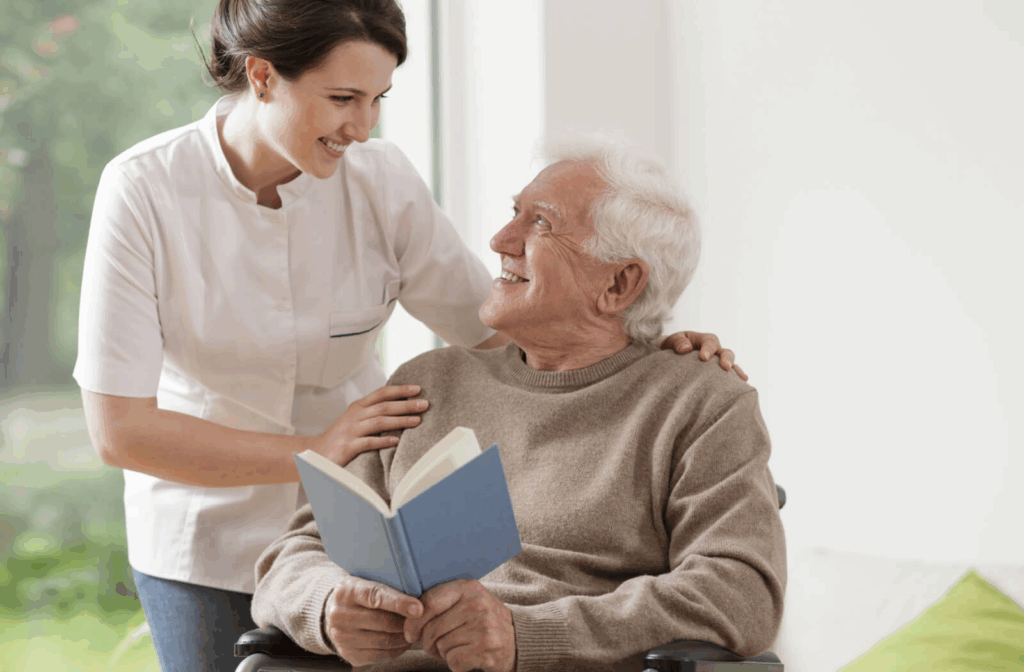 A resident in assisted living takes a break from reading their novel to smile at a caregiver during a quick check-in