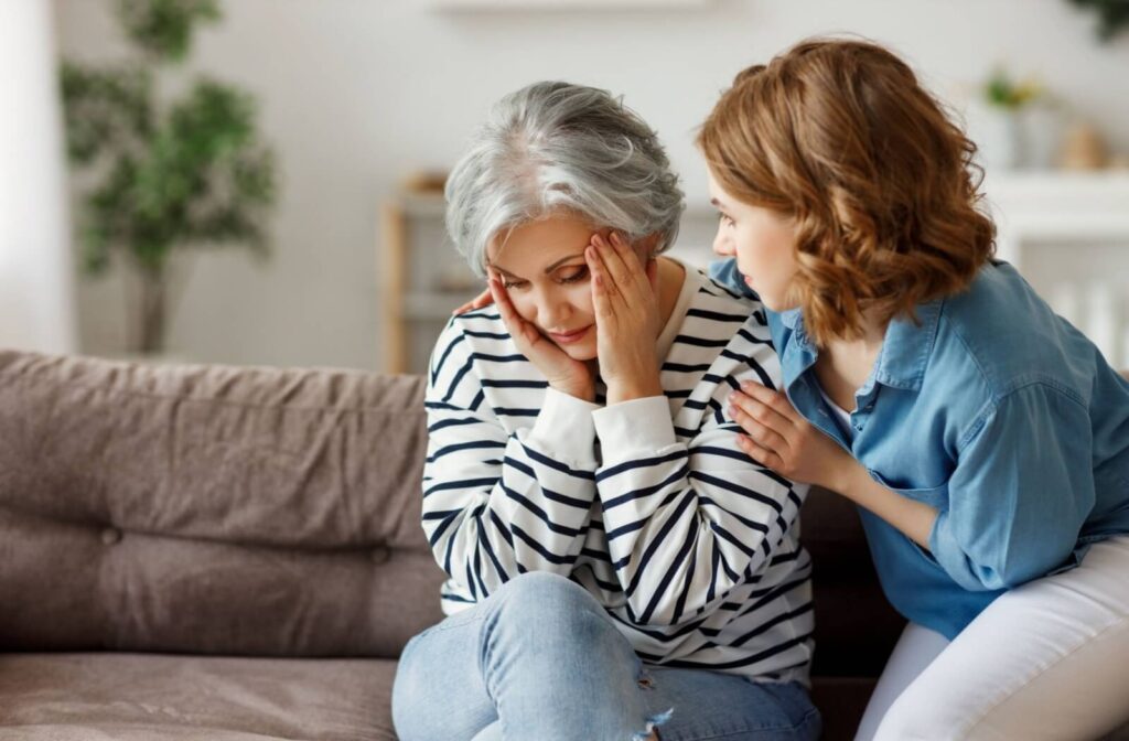 a senior and a carer sit on a couch completing a form